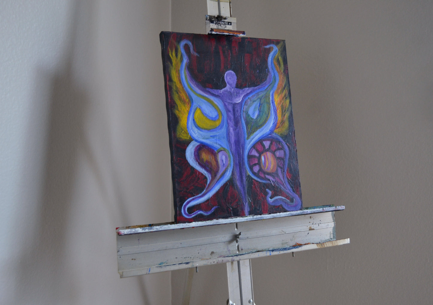 Purple man figure with wings painting on metal easel.