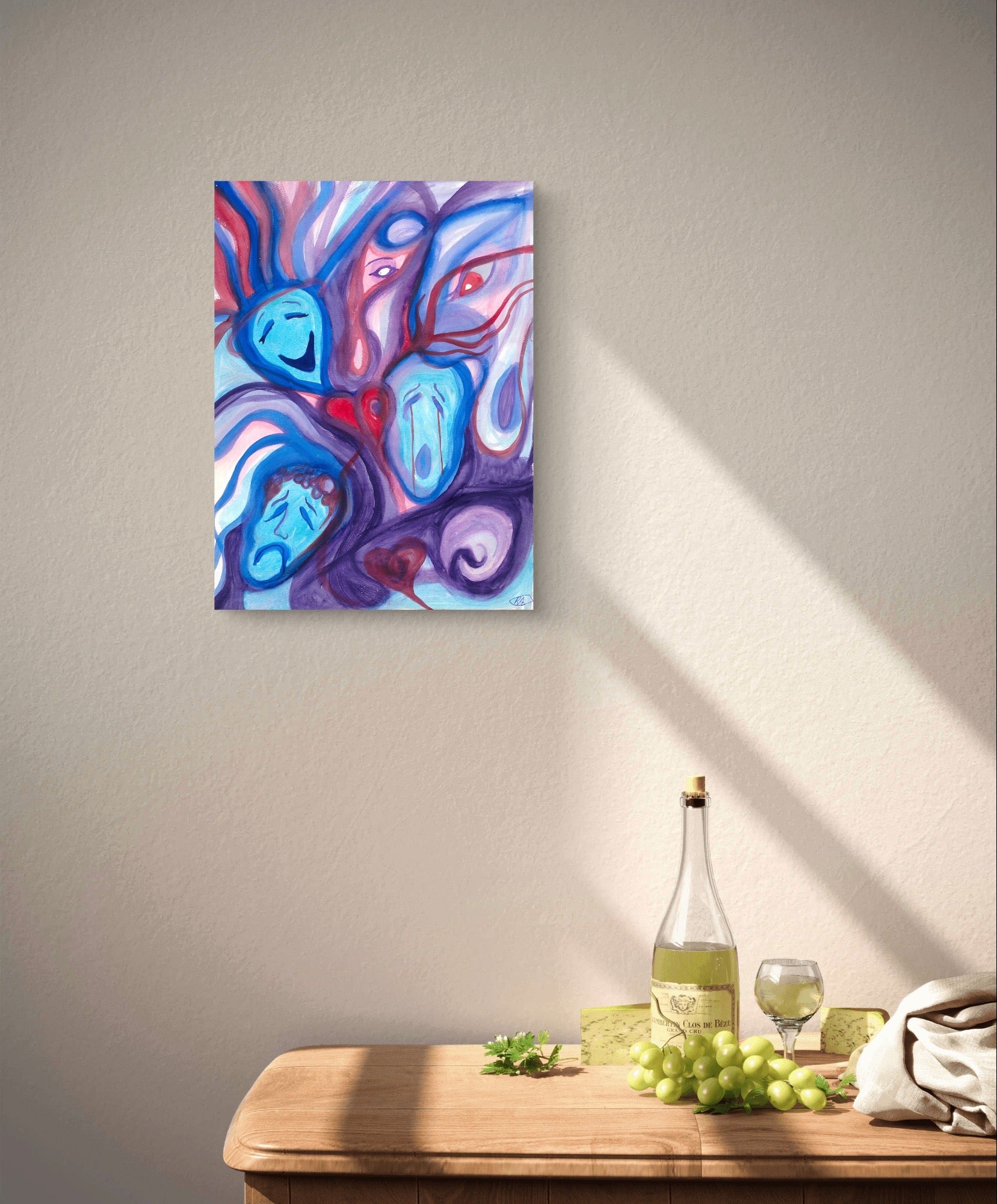 Mood artwork on white wall above wooden table with grapes and wine.